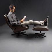 Example of someone sitting in the Eames armchair with matching foot rest pouffe