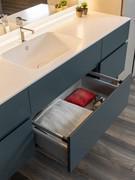 Close up of the white Corian® countertop with built-in washbasin and the inside of a basket drawer