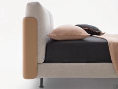 The leather-covered headboard extends sideways to wrap around the large cushions and part of the bed frame