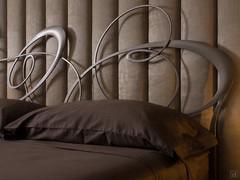 Lounge fabric boiserie combined with a bed (Ghirigori) with an impressive metal headboard