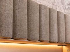 The upholstered slats composing the wall panelling can be covered in a wide range of materials (fabric, faux-leather, leather)