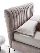 Detail of the shaped and slightly curved profile of the high quilted headboard with vertical stripes of the Joao bed