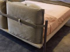 Detail of the rear headboard of the Cayman upholstered bed: the two cushions are supported by a painted metal bar and high wooden feet