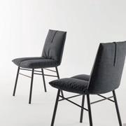 This upholstered modern chair has visible sewing that characterise the seat cushion, divided perfectly in 2 parts 