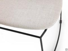 Close-up of the seat of the Chloe chair upholstered in fabric in a colour that contrasts with the lacquered metal structure