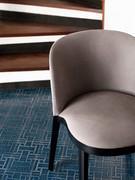 Detail of the seat with upholstered cushion supported by a solid wood frame that follows its curved profile