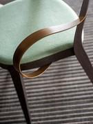 Detail of the armrests made of a single thin flat metal sheet, curved like a ribbon and passing from side to side under the backrest