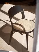 Detail of the Minima chair with thin metal armrests and Vienna straw seat panel