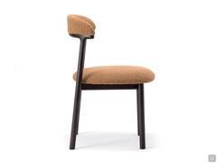 Side view of the Lisa chair showing how the rounded shapes of the upholstery are also reflected in the curved wooden profile of the backrest and the wooden tubular legs