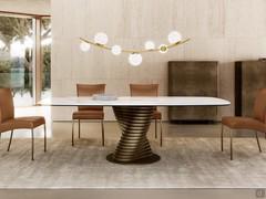 Front view of the living room design table Vortex: the central designer base matches the Maia sideboards in vintage brushed bronze lacquer, while the shaped ceramic top echoes the wall covering