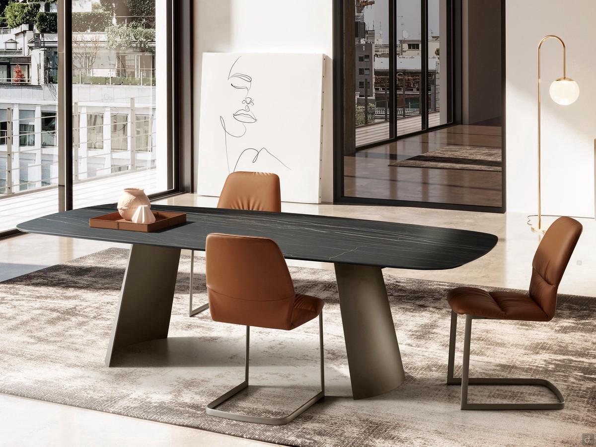 View of the Edwin fixed table with sail-shaped base from the front. Shaped tabletop in Matt Portoro ceramic and base in Titanium-finish painted metal.