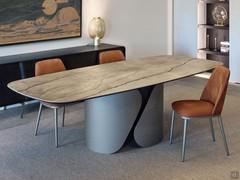 Three-quarter view of the Torquay table from which the sinuosity and design given by the shapes of the base shines through. The table is matched with Michela chairs from the same collection