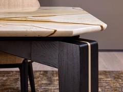 Detail of the base of the Lewis table, in solid Black Oak wood with a central metal insert in Sand Gold. Also noticeable is the particular shaping of the top, with the edges that follow the shape of the base