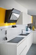 Detail of induction cooktop and furnishing hood on colored matte lacquered backsplash