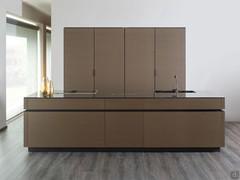 The island is the central operating area with integrated cooktop and sink, behind it the cabinets with retractable doors equipped