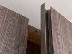 Detail of melamine door with full-height curved groove in gunmetal matte lacquered metal