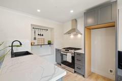 Gray kitchen with burners, designer hood, equipped island and refrigerator niche