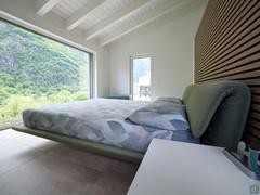 Spacious bedroom with high mansard ceiling and exposed wooden beams painted white.