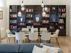 Large bookcase with plenty of space for books and collectibles, positioned behind an elegant table and comfortable chairs