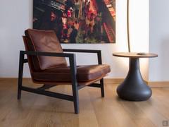 Special leather reading armchair with wooden frame Grey Oak essence. Original coffee table with Graphite metal frame and top resembling the section of a tree trunk.