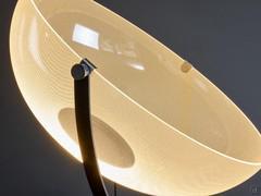 The thin metal frame, which connects the cone of light to the base, is available either painted white or black and allows the lamp to be oriented according to one's needs