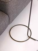 Detail of the base: a slim circular tube in burnished brass matching the vertical upright and containing the wires