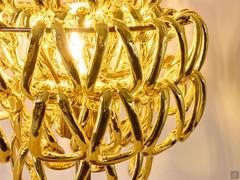 Gold crystal hooks meticulously attached to each other and in turn to the structure create an almost illusory optical effect, with a see-through effect of the light source