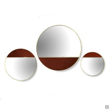 Cayos is a round brass mirror with one side covered in fabric, velvet and leather