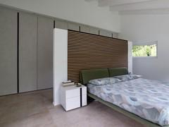 Room design with centre bed, partition wall and linear wardrobe