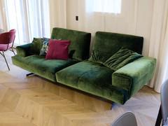 Linear green velvet sofa with low back, wide arms, adjustable seat.