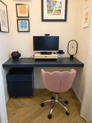 Home office study corner with blue hanging shelf, pink office chair, blue chest of drawers with wheels.