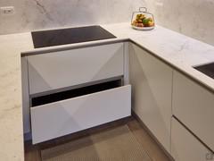 Kitchen with induction hob and storage cabinets with large baskets.