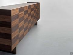 The hypnotic surface pattern of inlaid wood outlines the sections of the doors and drawers