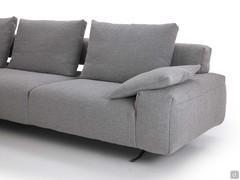 Detail of the Shirley sofa with open back, feather cushions on the backrest and low armrest