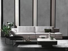 Linear Omega sofa with armrests that recline to either side and, when lowered, create a single plane with the cushions as an extension of the wide seats