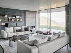 Living room furnished with two Phil sofas by Bonaldo in fabric. One of the two features the optional magazine rack armrest, while the pouf with matching leather tray completes the room