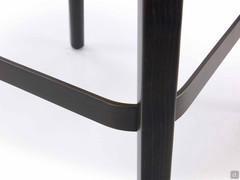 Detail of the heat-treated stained beech frame combined with the bronze-painted metal footrest