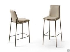 View of the Dalila stool from the front and back. Kitchen countertop and snack-bar countertop versions. Leather upholstery and metal legs in a Bronze finish.