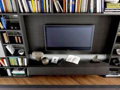 Detail of oak veneered TV panel with suspended storage cabinets and LED lighting