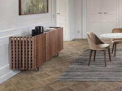 Le buffet moderne design en bois Astor avec porte à lattes de noyer massives dans un salon formel marqué par la chaleur du bois