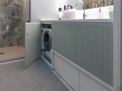 Meuble de salle de bains sur mesure avec socle pour lave-linge avec porte, paniers de rangement et paniers à linge.