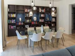 Salle à manger équipée d'une table en verre et en pierre, de chaises en velours et en métal, d'une bibliothèque en mélaminé et laqué