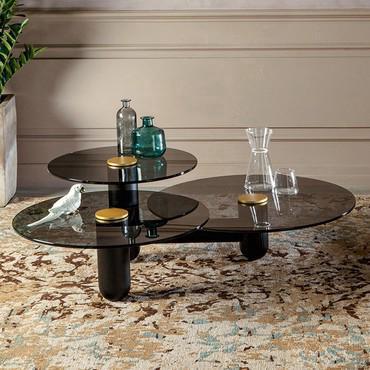 Table d'appoint avec trois plateaux Cosmo caractérisé par : structure en frêne noir, plateaux en verre fumé transparent, et cercle central en métal laqué or mat.