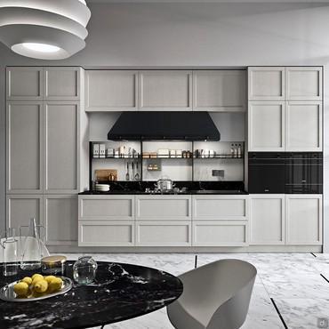 Cucina lineare con frigo, forno e microonde integrati nelle colonne laterali. Piano di lavoro centrale con cappa stile industriale.