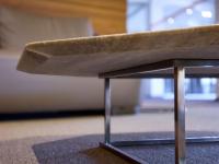 Dettaglio del sottopiano del tavolino Alex, con la lastra di marmo bisellata e appoggiata direttamente alla struttura in metallo