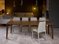 Tavolo Nelia in finitura noce abbinato alle sedie Corinne con rivestimento in pelle, materiali classici per un living moderno
