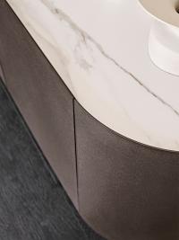 Detail of thin doors and curved structure covered in bronze-embossed metal: golden calacatta ceramic top