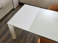 Main dining table with extra-clear glass top back-lacquered in RAL 1013: detail of the extension in white melamine, also available in canvas and grey melamine or in matt lacquer matching the main top.